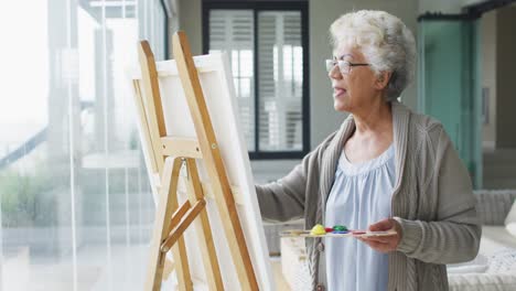 African-american-senior-woman-painting-on-canvas-at-home