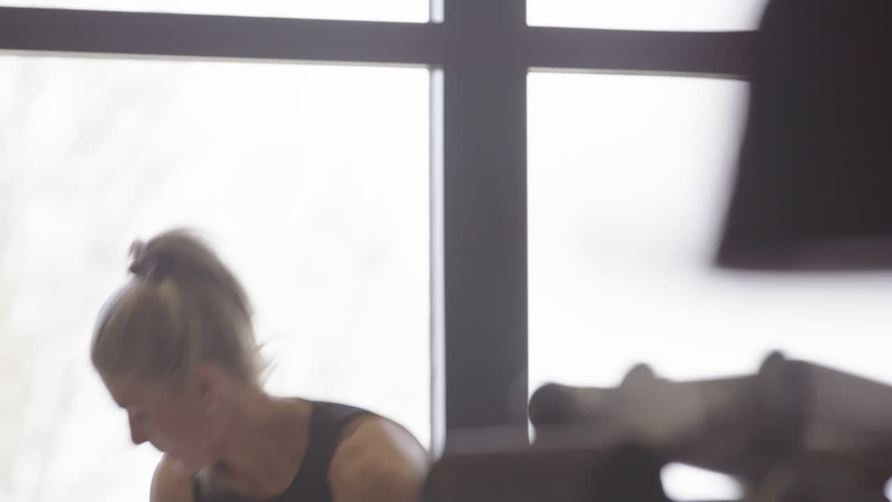 체육관 에서 집중적 인 금발 여자 운동 선수 가 운동 을 시작 하기 위해 셔츠 를 벗는다