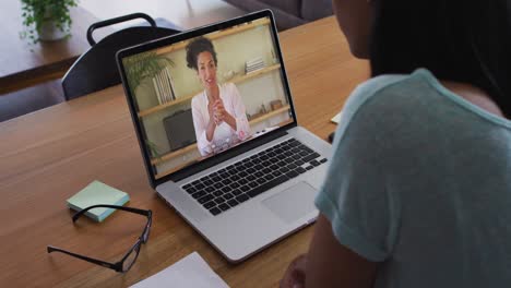 Mid-section-of-african-american-woman-having-a-video-call-with-female-colleague-on-laptop