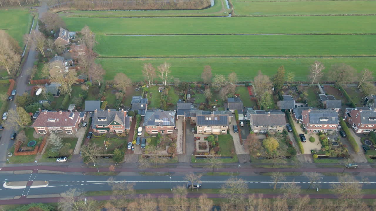 시골 지역의 고요한 도로 옆 옥상에 태양 전지판이 있는 독립형 주택의 공중 - 무인 항공기가 뒤로 날아갑니다.