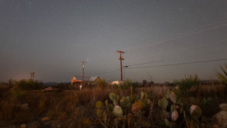 stars and meteors rising over a west texas landscape with telephone poles, cactus, and a small house