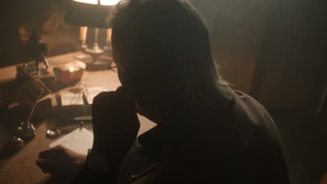 older passionate man evaluates an old watch in his office at night