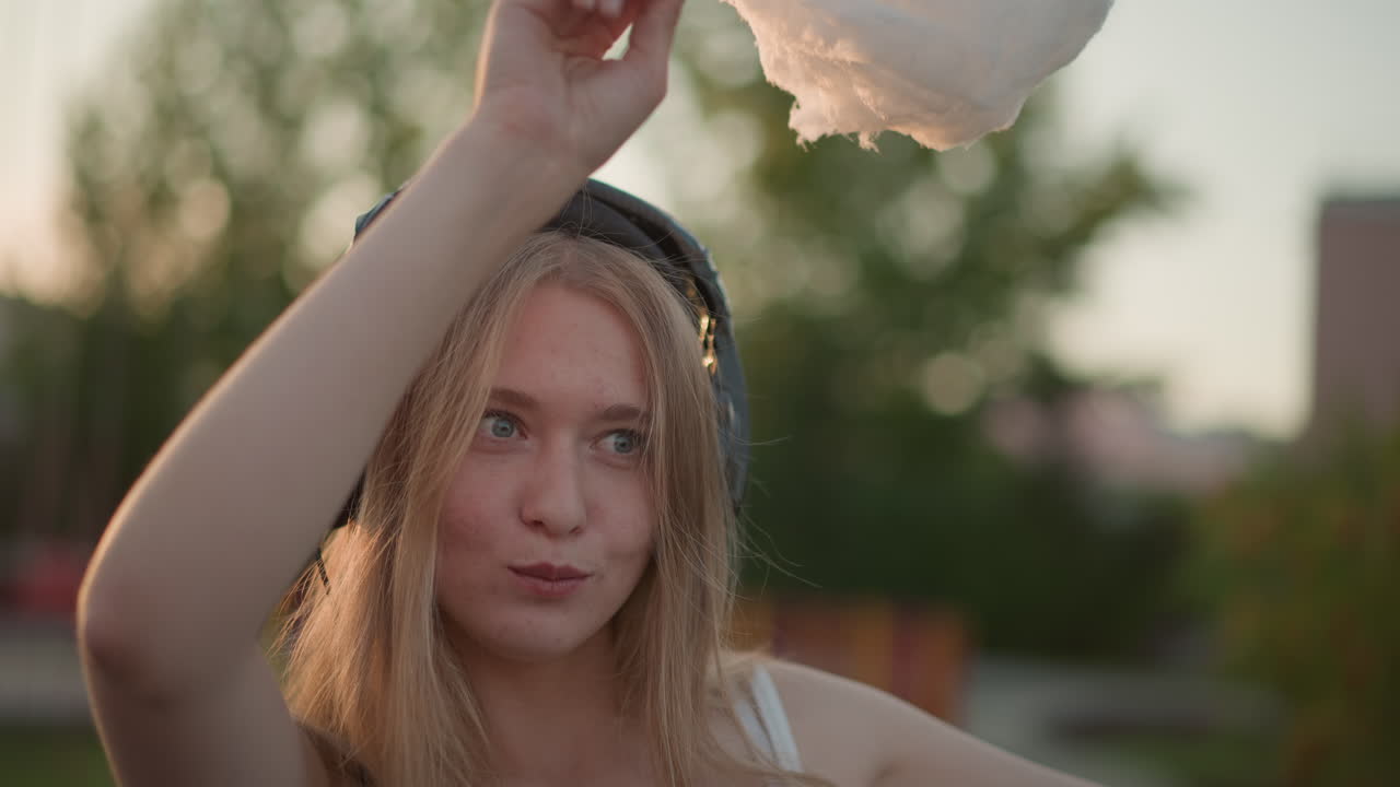 Ballo celebrativo al tramonto, ragazza energica che volteggia con lo zucchero filato al festival del tramonto, ballo spensierato e celebrazione vivace mentre il tramonto estivo illumina momenti gioiosi
