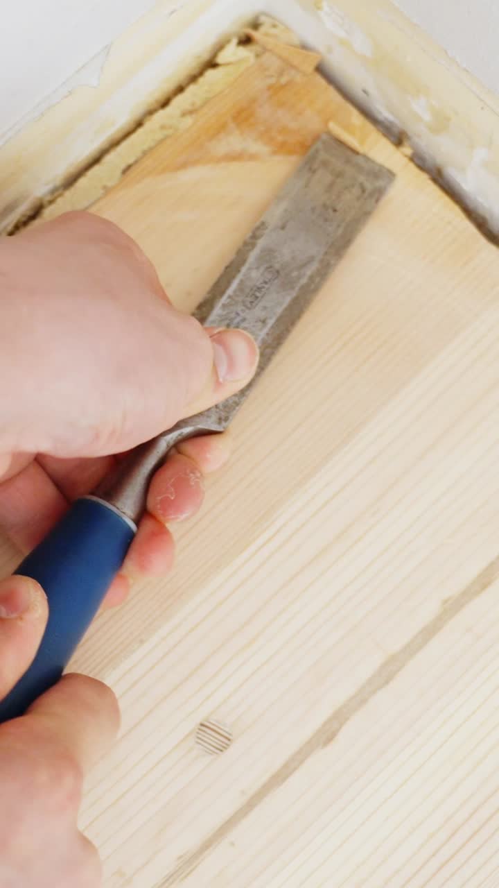 Hands chiseling wood for renovation, precise work, focused effort, vertical