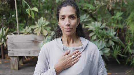 focused biracial woman practicing yoga in sunny garden, slow motion