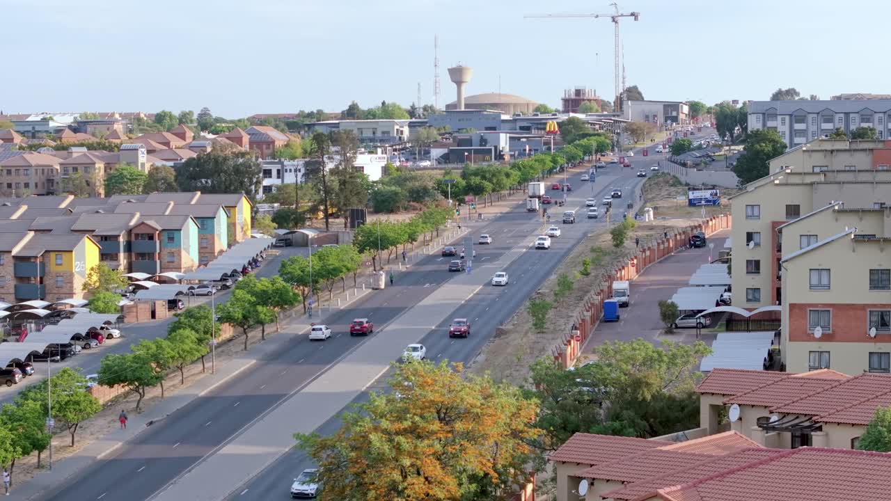 Aerial 4K footage of cars moving on a road between apartment blocks in Midrand, Johannesburg, South Africa. Daylight, clear sky, midday, ideal for metropolitan transitions