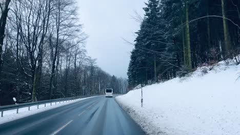 Lines-bus-drives-through-a-winter-landscape-on-a-road-through-the-snow-with-trees-on-the-side