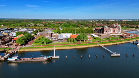 flying closer to the bright sunny lakefront of lelystad, the netherlands. view on the historical museum and green scenery of the city.