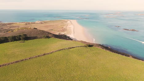 Flight over Shell Beach Herm, the Channel Islands with golden sand clear turquoise sea at low tide with rocks of “The River” showing on clear sunny day