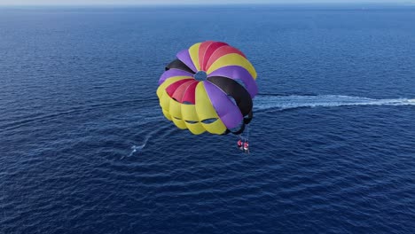 aerial back view of double parasailing wing over the ocean tugged by a motorboat, wide arc shot