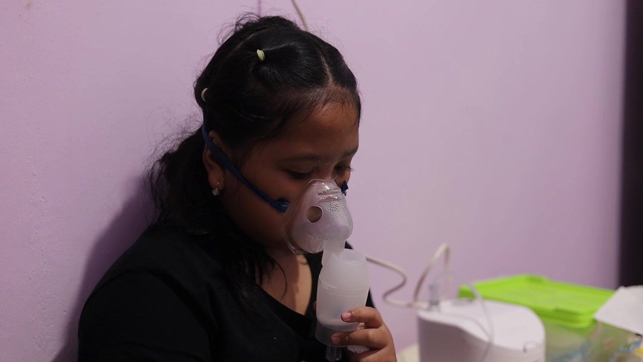 Una bambina malata che usa un nebulizzatore a casa