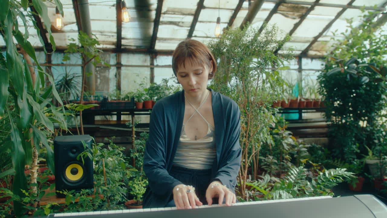 Female Performer Playing Musical Keyboard in Greenhouse with Tropical Plants