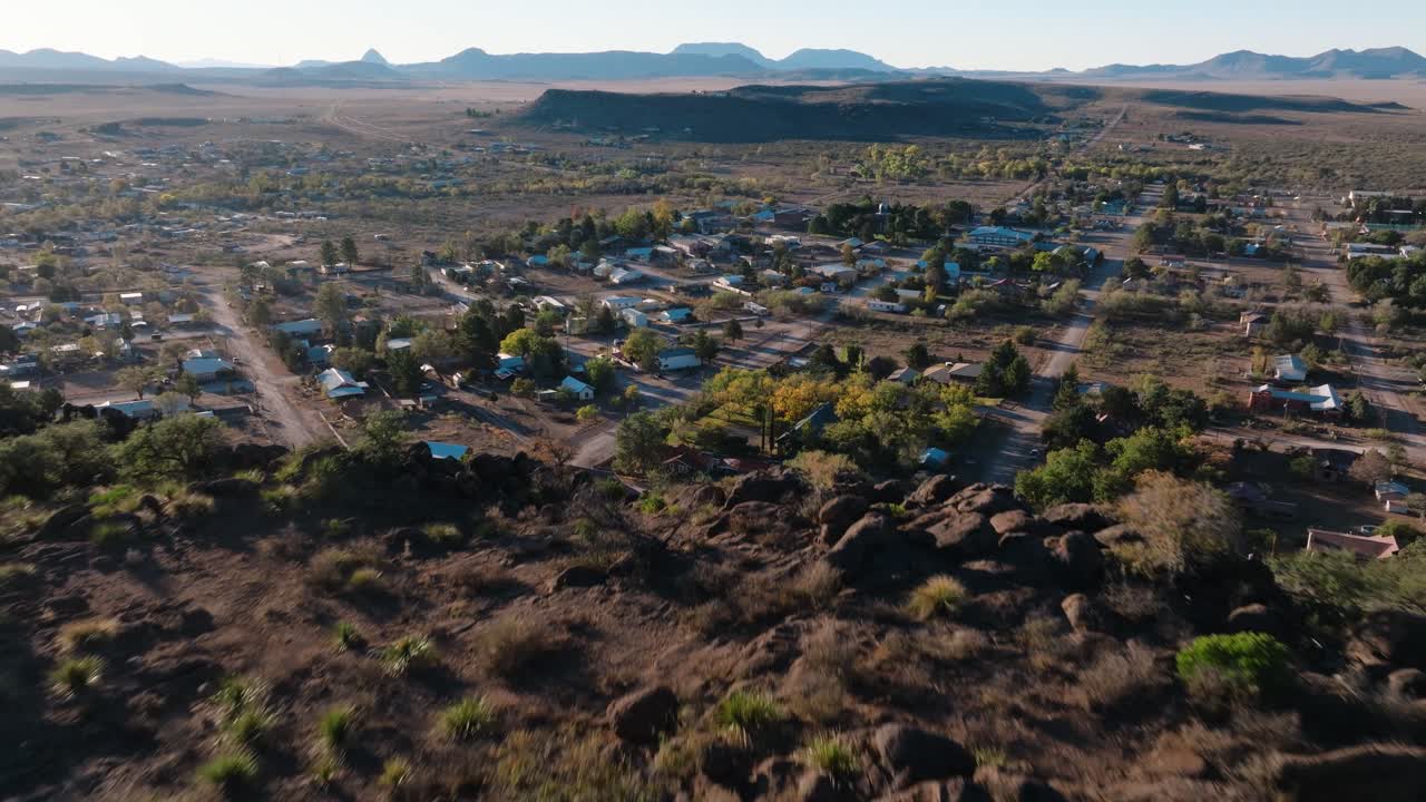 Pulling away to reveal mountaintop overlooking rural Texas Town at Sunrise, Fort Davis in West Texas small town golden hour drone city orbit in 4k
