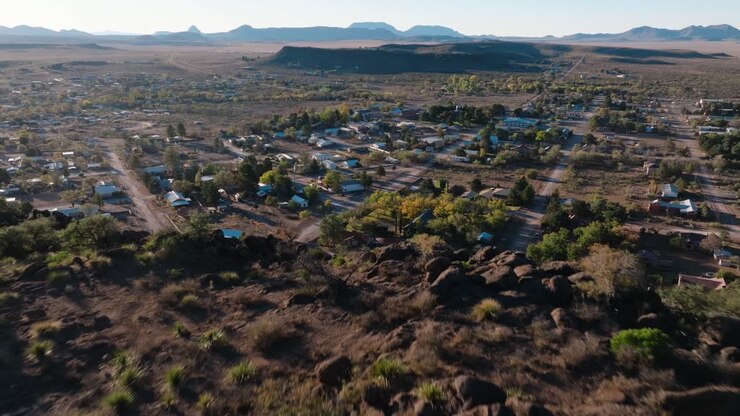 Pulling away to reveal mountaintop overlooking rural Texas Town at Sunrise, Fort Davis in West Texas small town golden hour drone city orbit in 4k