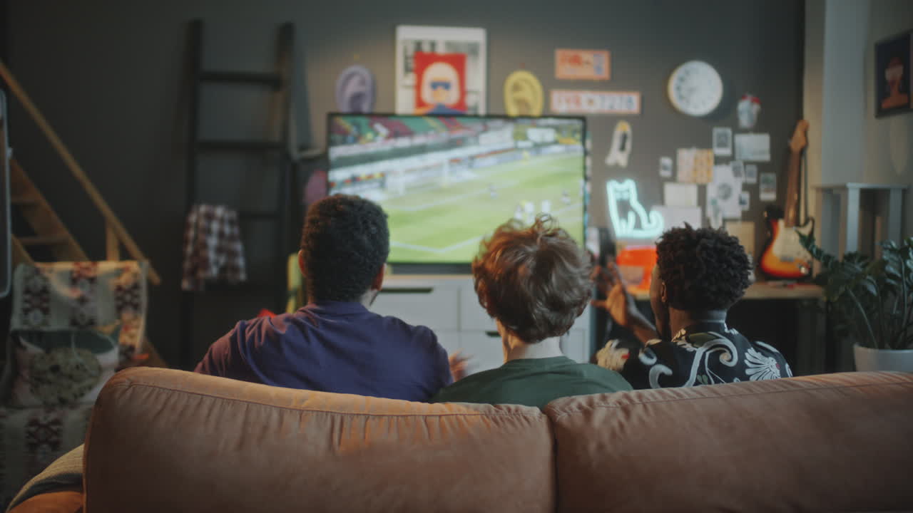 Young Men Watching Soccer Match on TV and Cheering at Home