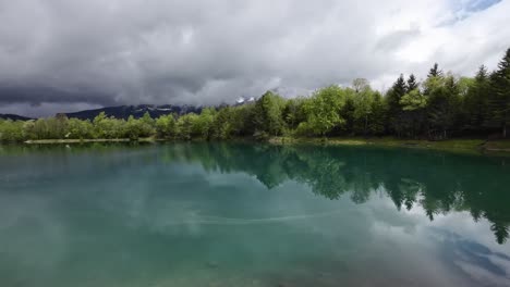 turqoise fishing lake in nenzing austria surrounded by forest on a cloudy day