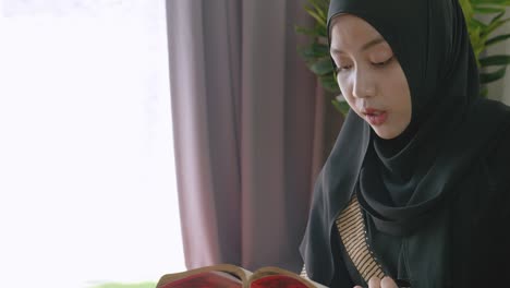 muslim women sit reading the book and pray prayer by hand in the air in the home, belief quran culture