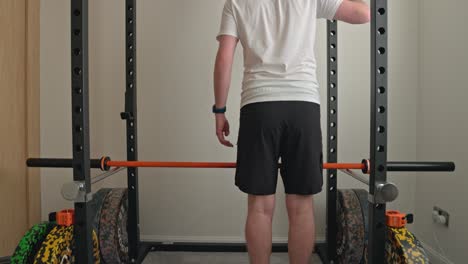 static shot of a man lifting a barbell back onto the rack ready to workout