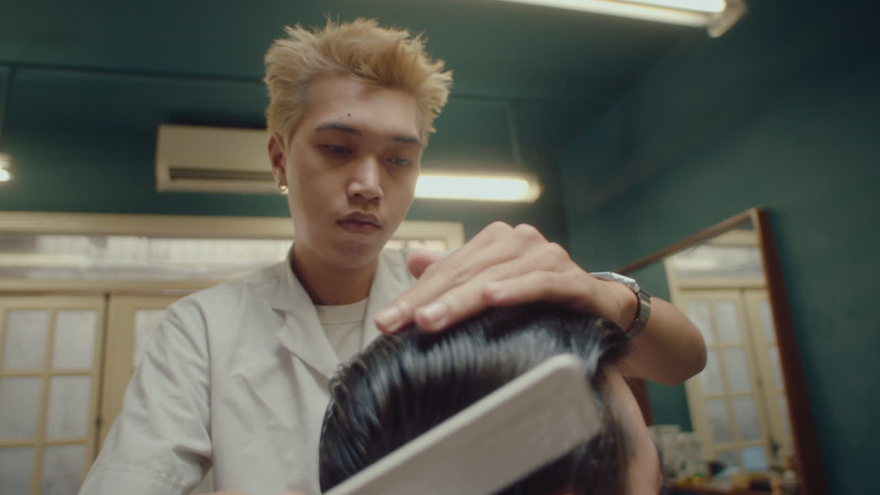 Professional Asian Barber Combing Hair of Man
