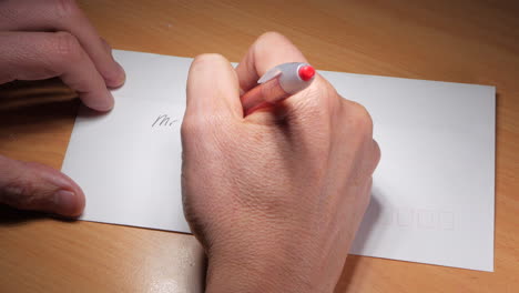 man writes an address on a white envelope