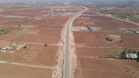 Blick-Aus-Der-Vogelperspektive-Auf-Entfernten-Verkehr,-Der-über-Eine-Einzige-Straße-Im-Ländlichen-Kenia-Fährt