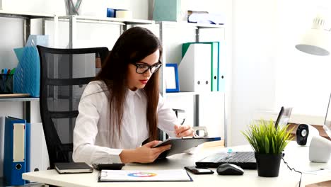 businesswoman in black glasses filling documents and working on laptop in modern office
