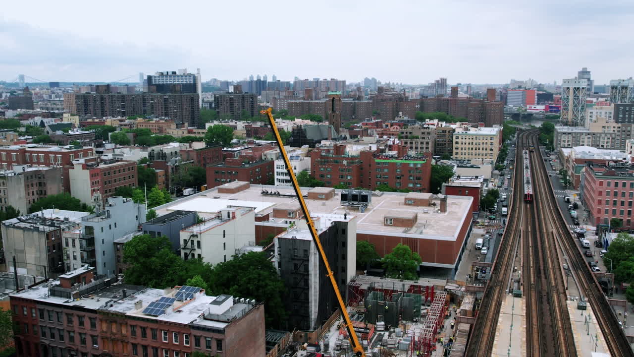 vista aérea con vistas a una grúa que levanta materiales en un sitio de construcción en una estación de tren en cloudy harlem, nyc