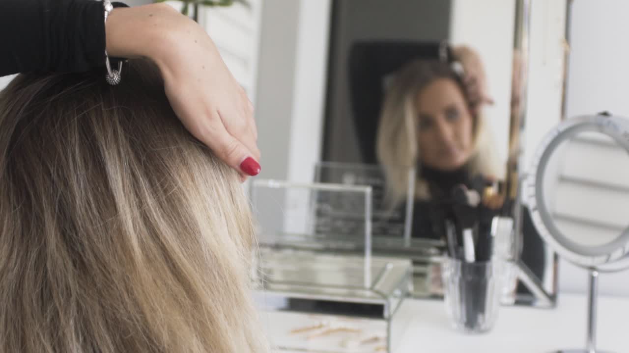 mujeres mirándose en el espejo y poniéndose una horquilla en el pelo mientras se prepara