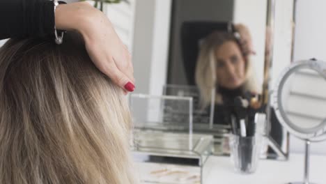 women looking in the mirror and putting a hair-clip in her hair as she gets ready