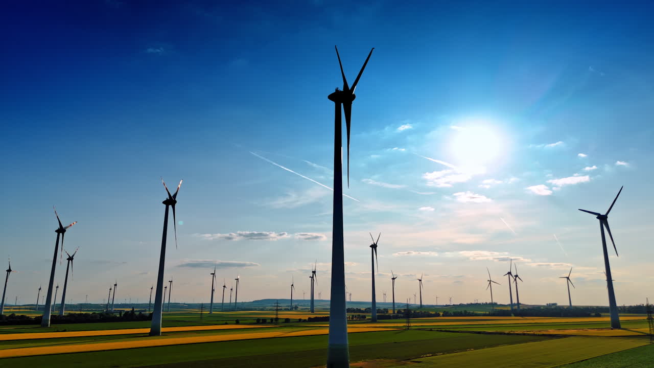 Turbines produce green energy. Expansive fields dotted with wind turbines harnessing wind energy beneath a bright sky during the day