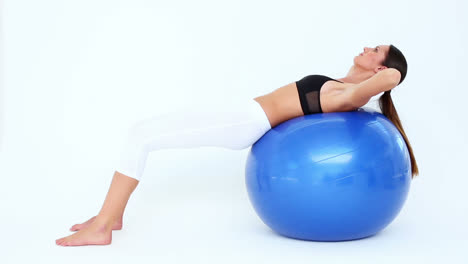 fit woman doing sit ups on blue exercise ball