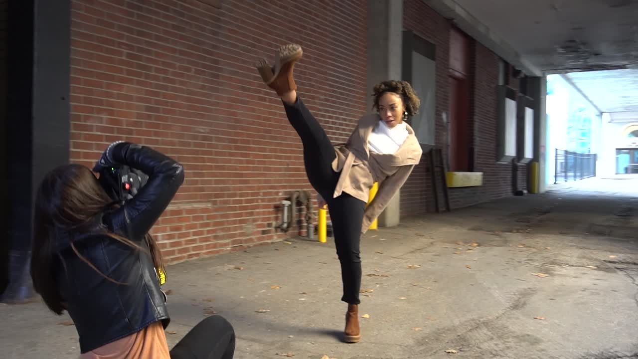 Black model poses for a photographer in an alleyway.