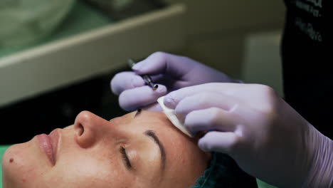 blackheads removal procedure at cosmetologist's. female client wearing a cap lies on the couch having face skin care. close up.