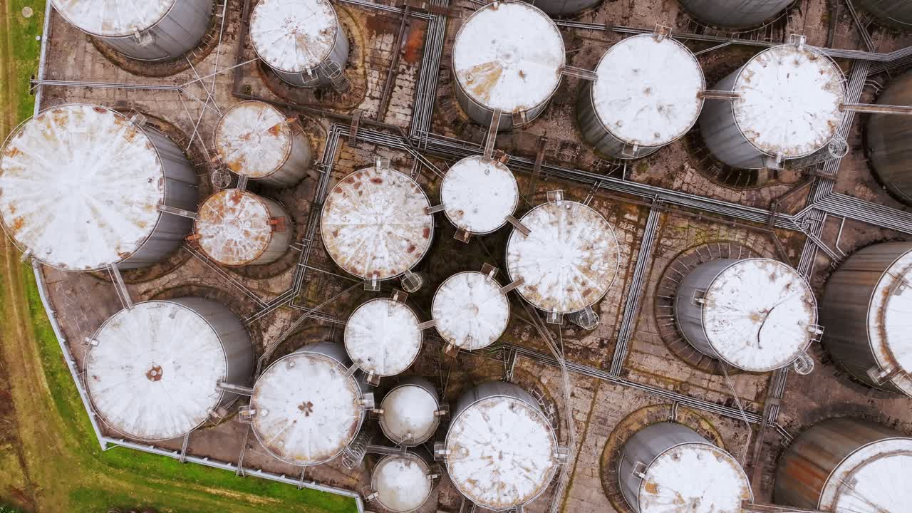 Aerial cinematic vertical drone footage over oil tanks, symbol of old energy era