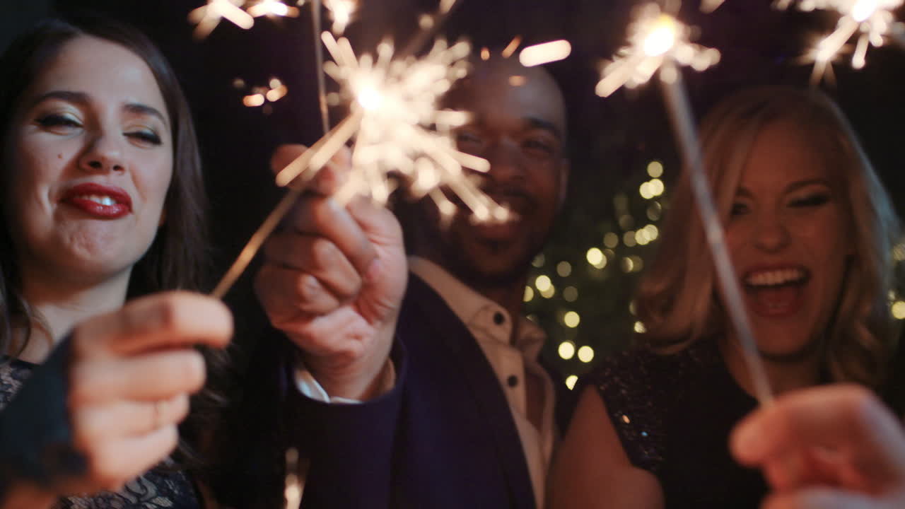 sexy group of friends at glamorous party lighting sparklers