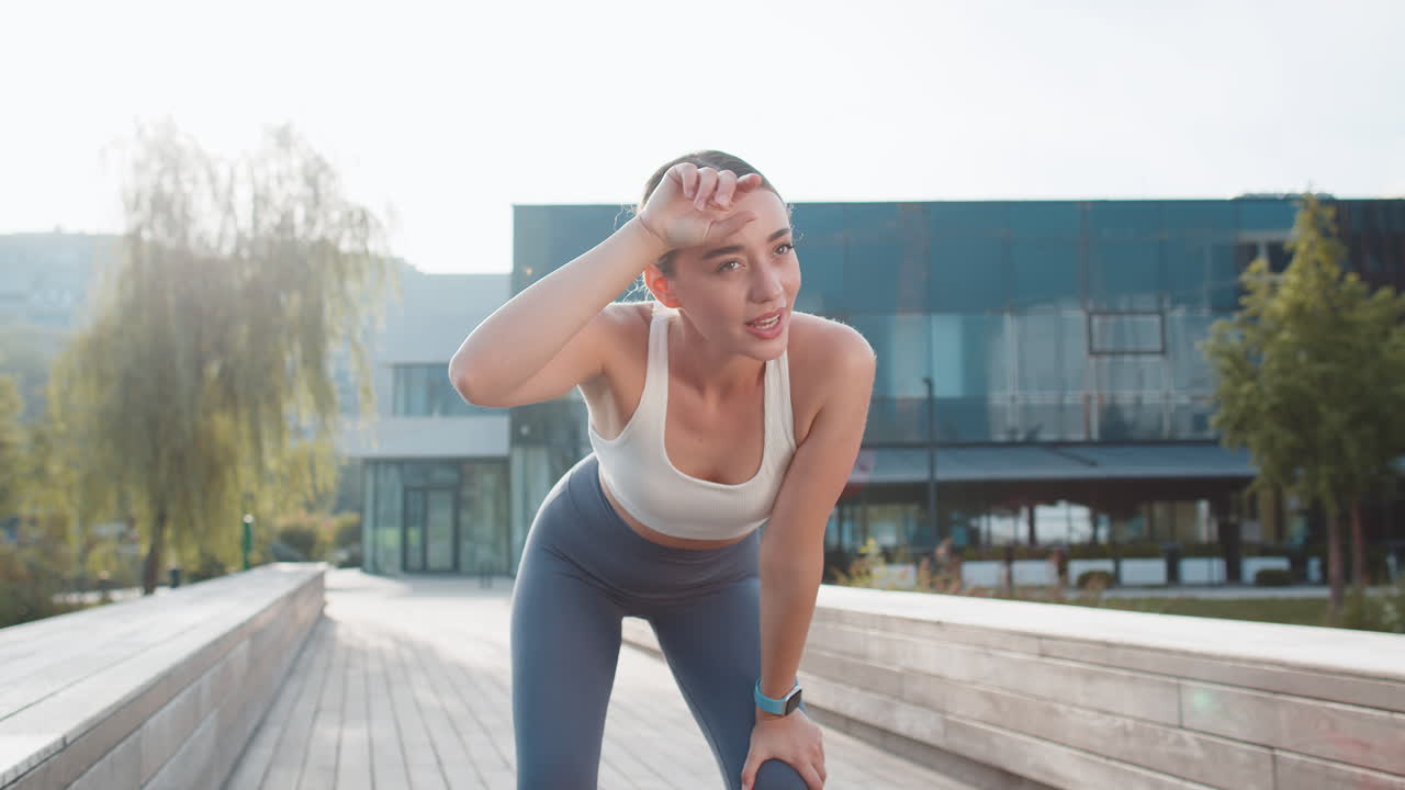 Athletic runner woman looks at smart watch device fitness bracelet checking heart rate after jogging