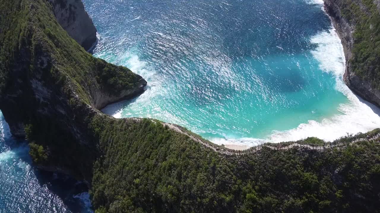 Bali coastline aerial showcasing turquoise beach meeting rugged cliffs. Scenery highlights island paradise, travel destination. Ideal for vacation, tourism or Bali visuals.