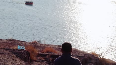 isolated man sitting at mountain top with lake view from flat angle video is taken at kaylana lake jodhpur rajasthan india
