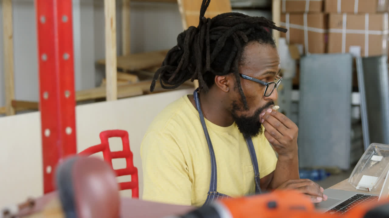 Carpenter having breakfast while using laptop 4k