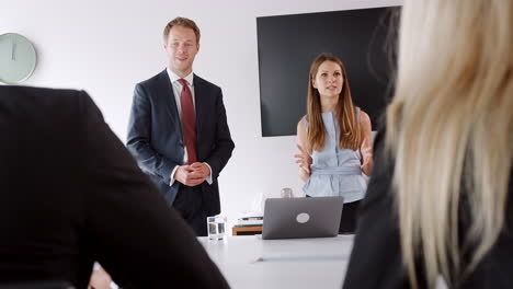 joven hombre de negocios y mujer de negocios dirigiéndose a una reunión de grupo en torno a la mesa en el día de evaluación de reclutamiento de graduados