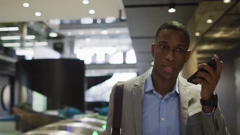 African-american-businessman-talking-on-smartphone-in-corridor-of-modern-office