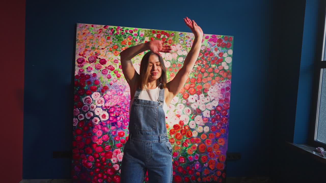 Mujer alegre bailando frente a una vibrante pintura floral