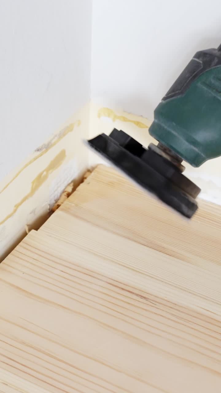 Precision tool spins to level a wooden surface during DIY renovation - vertical