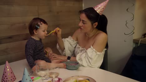 mother feeding daughter at birthday party