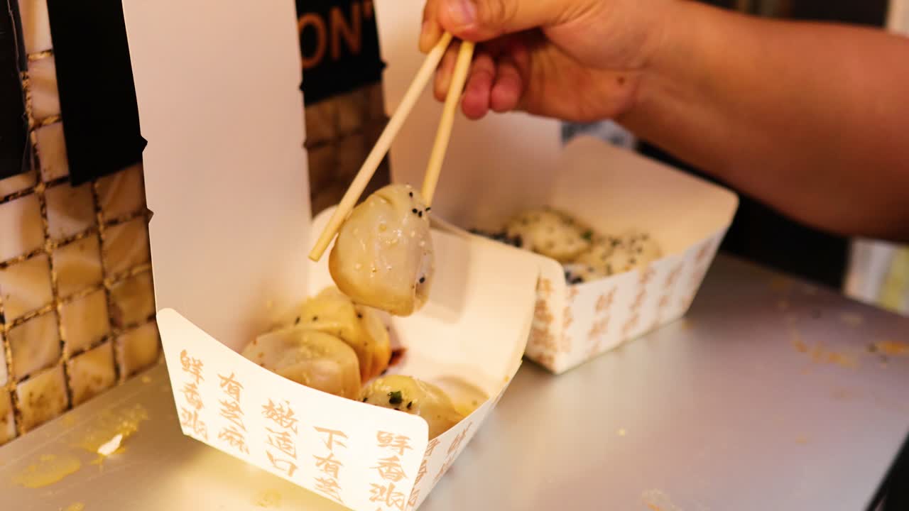 Chopsticks picking fried buns from a box