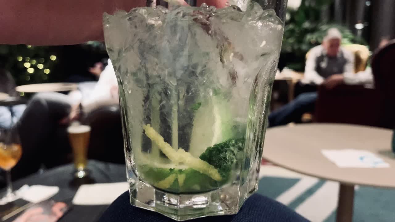 persona revolviendo y empujando cal de cóctel mojito en el bar del hotel, cerrar