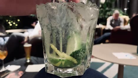 person stirring and pushing lime of mojito cocktail in hotel bar,close up