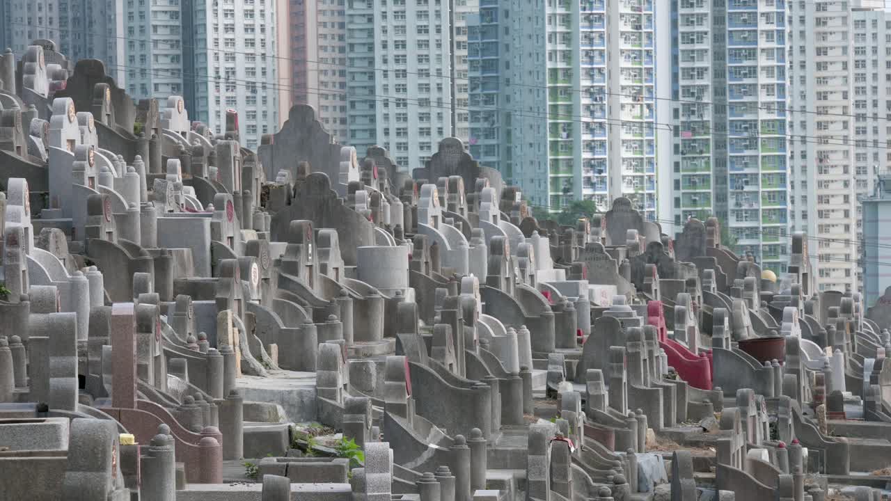 View of hundreds of tombstones at a crowded cemetery as residential buildings are seen in the background