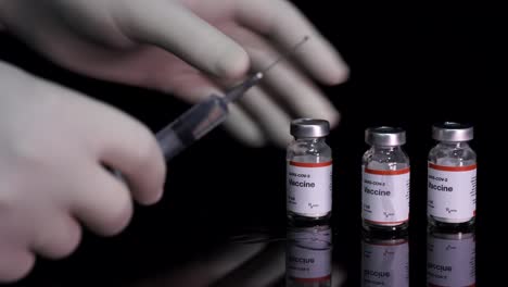 nurses hands preparing syringe from covid-19 vaccine bottle ready to injection