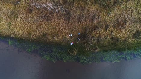 Plastikmüll-Am-Ufer-Eines-Kleinen-Flusses-Verstreut,-über-Kopf-Steigende-Antenne